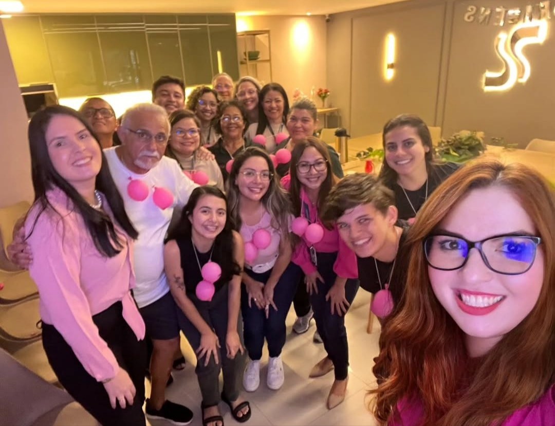 Equipe reunida em ação interna com temática rosa