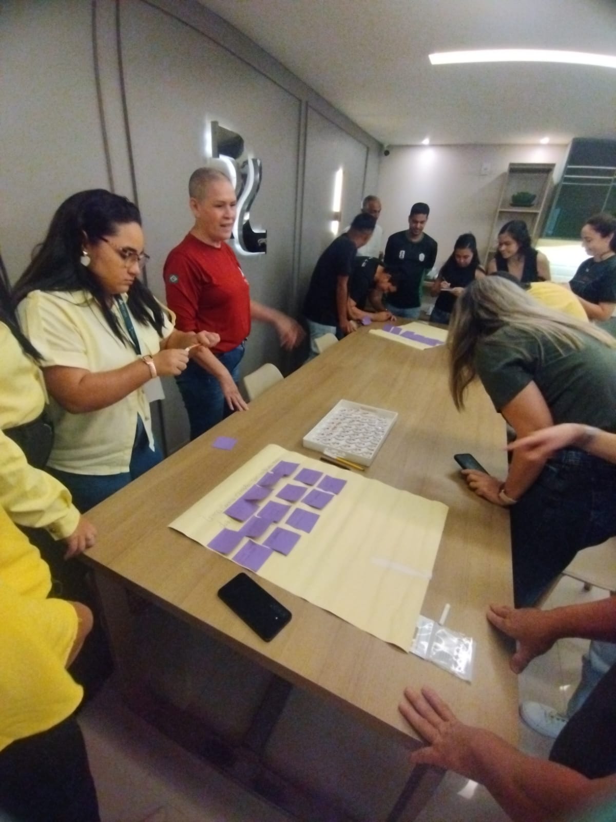 Dinâmica corporativa conduzida por Esther Faria com participantes em sala de reunião